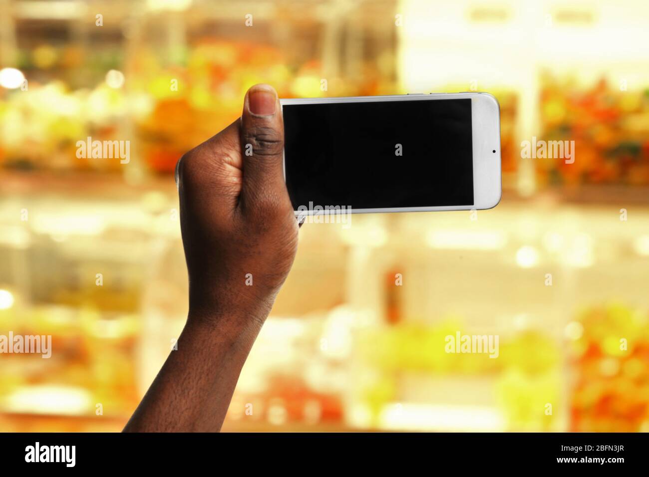 Mans hand shows mobile smart phone, blurred background Stock Photo