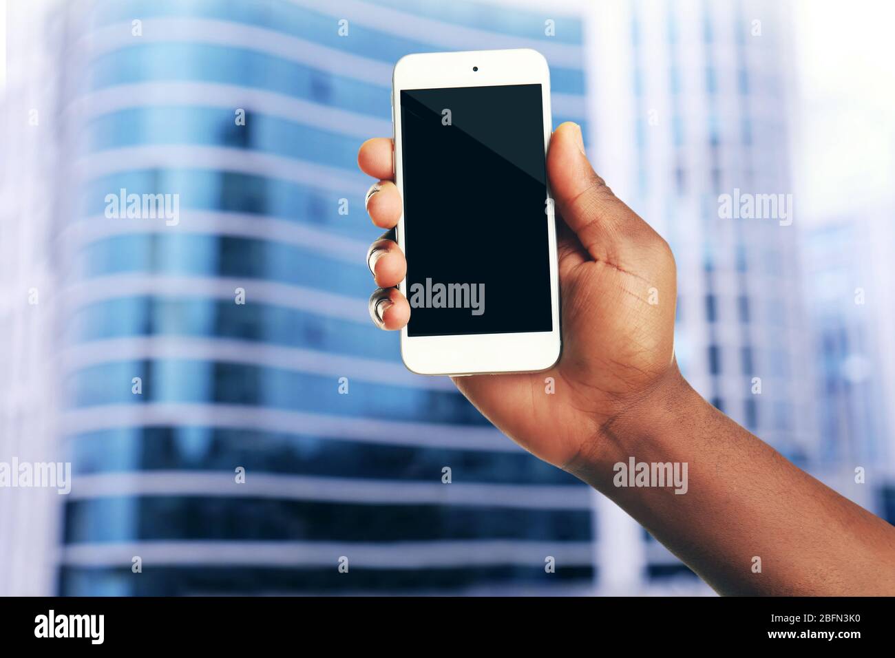 Mans hand shows mobile smart phone, blurred background Stock Photo