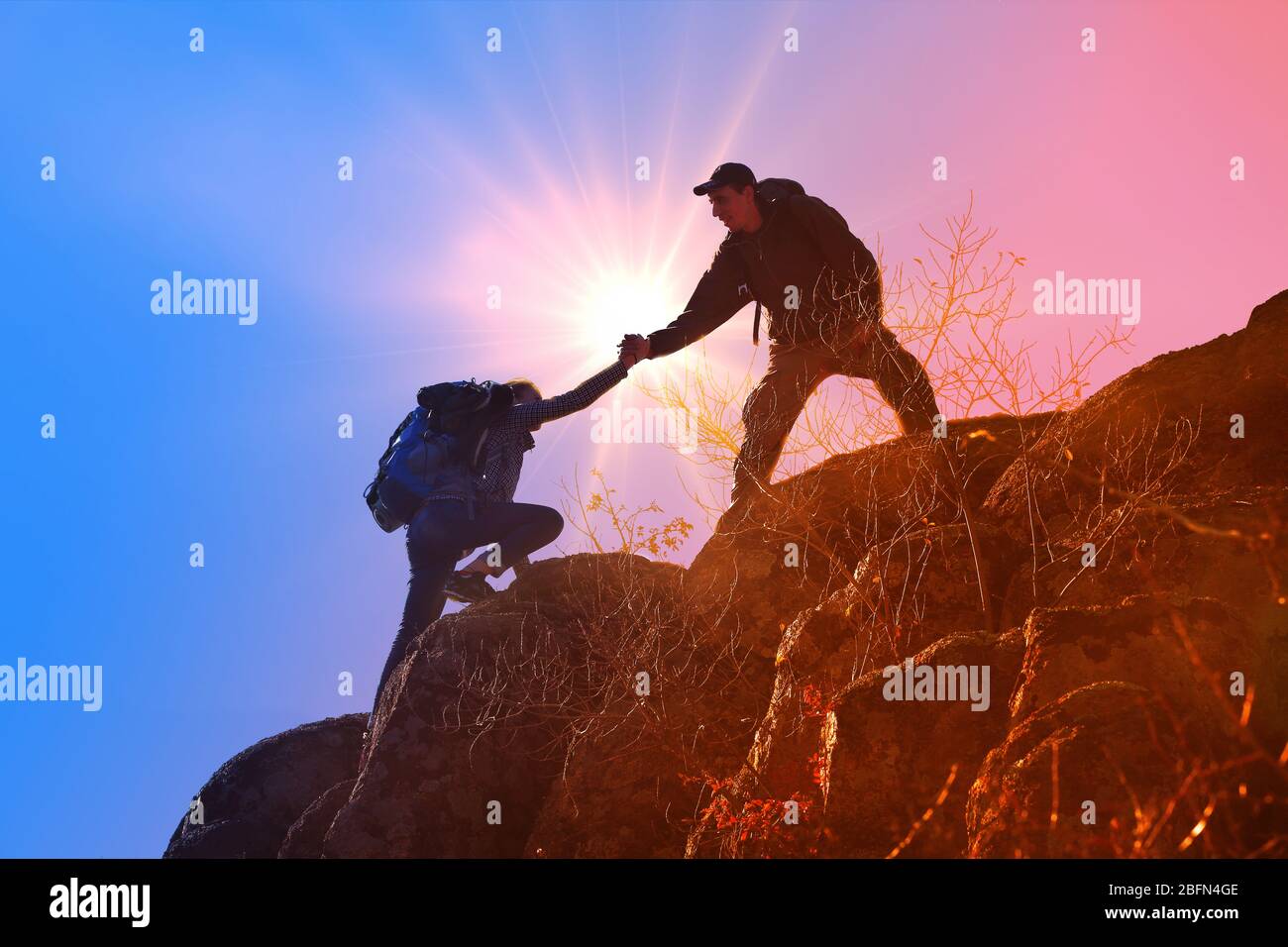 Helping hands with sunlight between two climbers Stock Photo