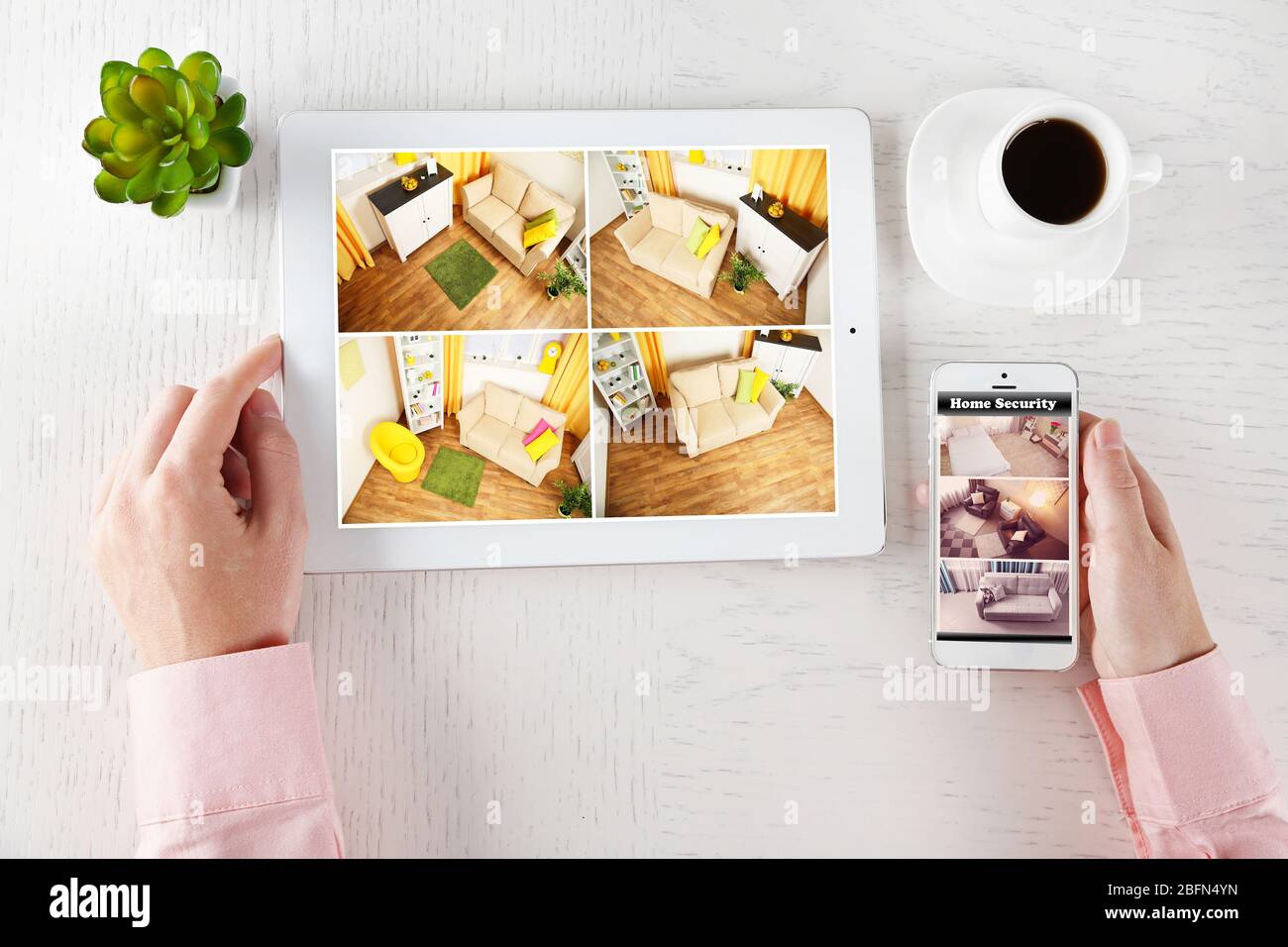 Male hands with tablet and phone on white table. Home security system concept Stock Photo