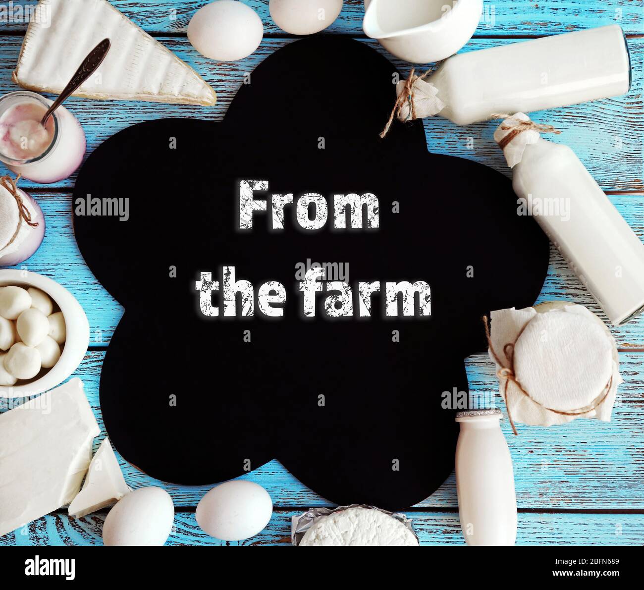 Text From the farm in frame of fresh dairy products on blue wooden table Stock Photo