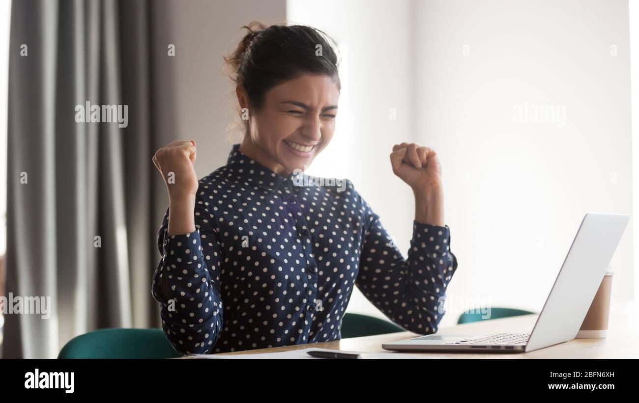 Excited happy indian employee celebrating success at work Stock Photo