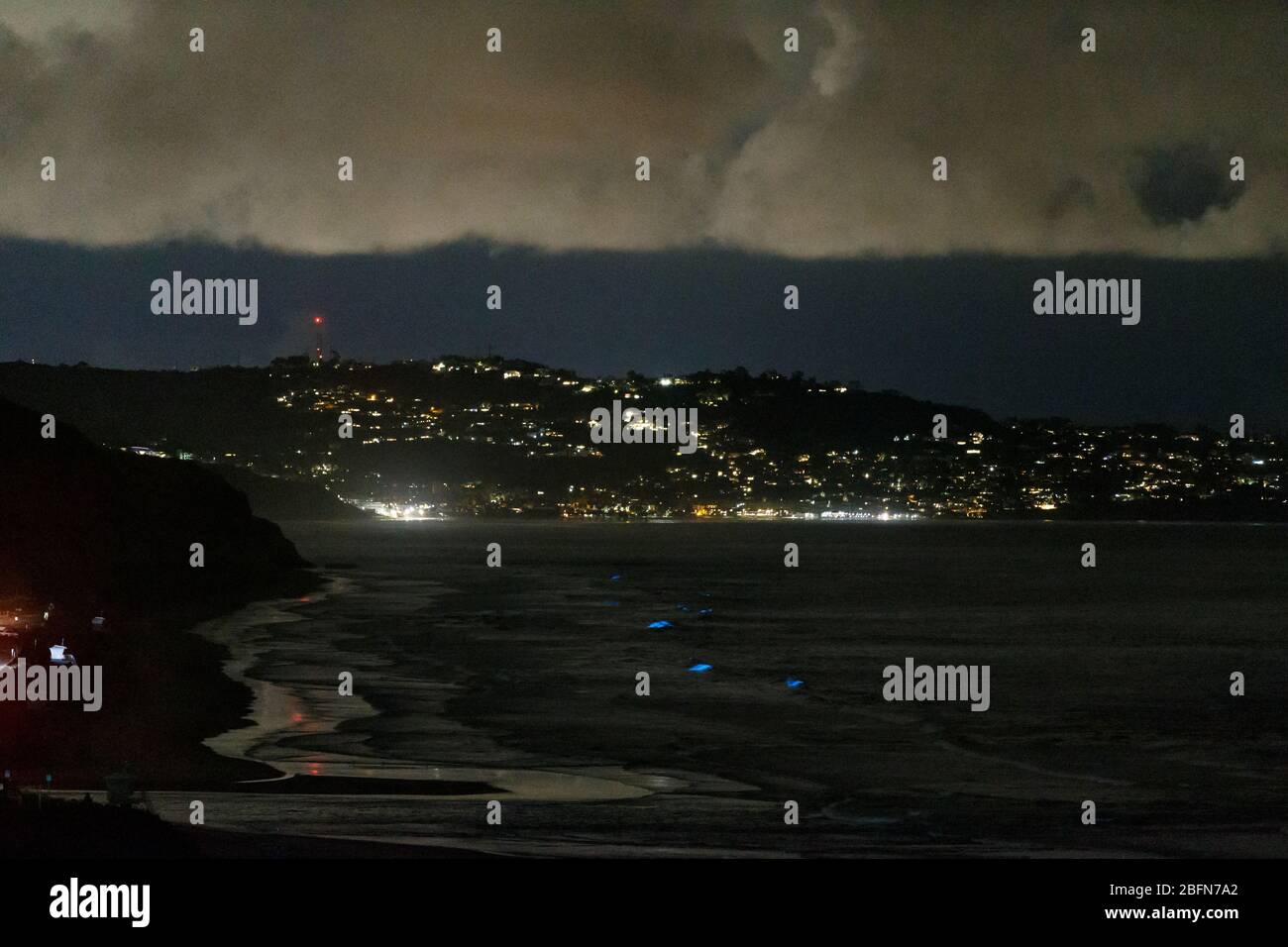 Ocean waves glow with bioluminescence during a red tide event in San Diego, California. Stock Photo