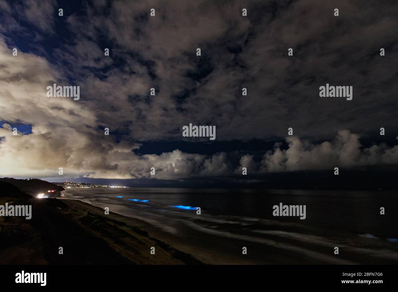 Ocean waves glow with bioluminescence during a red tide event in San Diego, California. Stock Photo