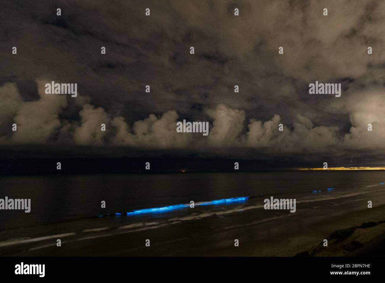 Ocean waves glow with bioluminescence during a red tide event in San Diego, California. Stock Photo