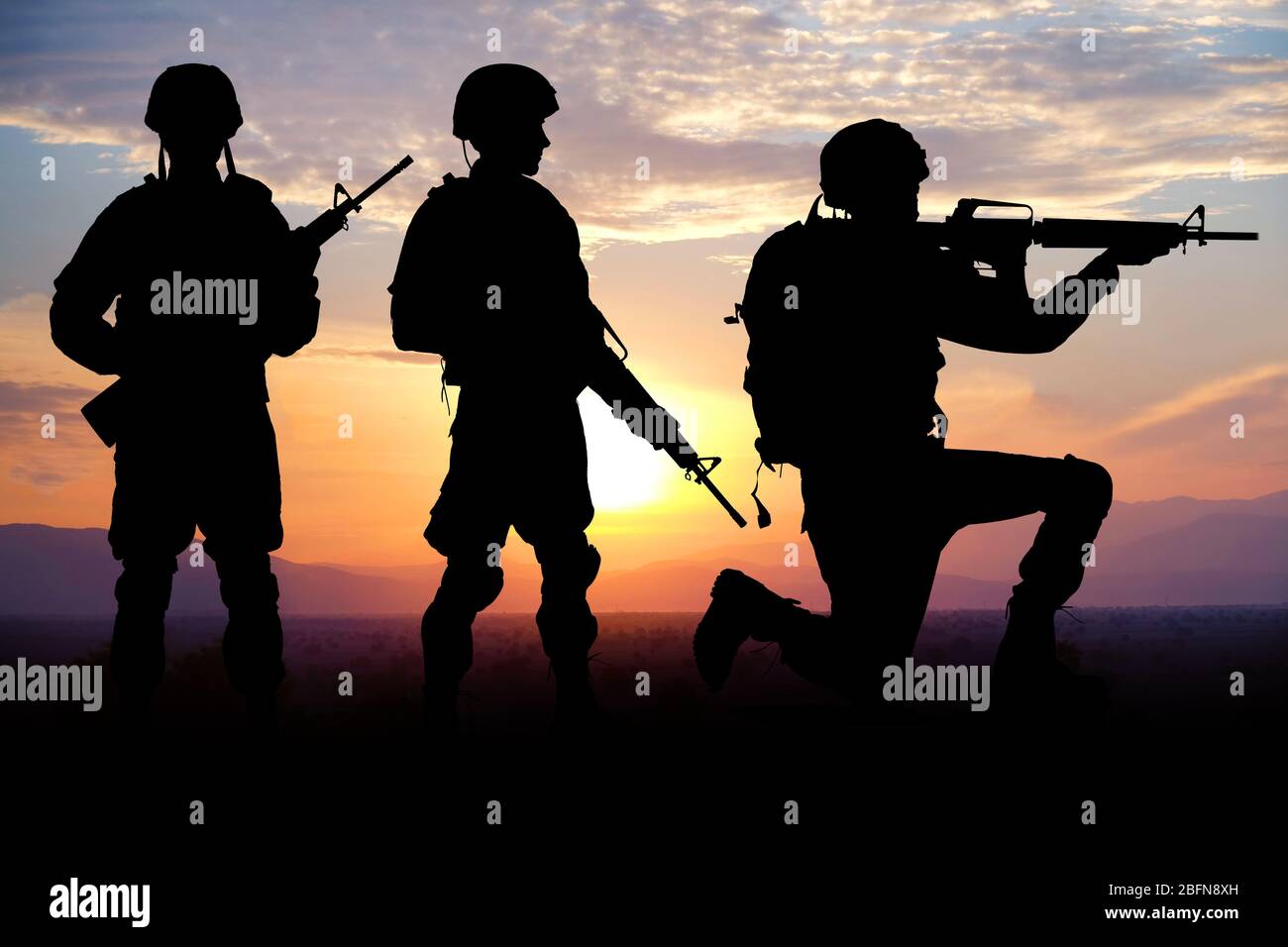 Silhouettes of soldiers on sunset background. Military service concept. Stock Photo
