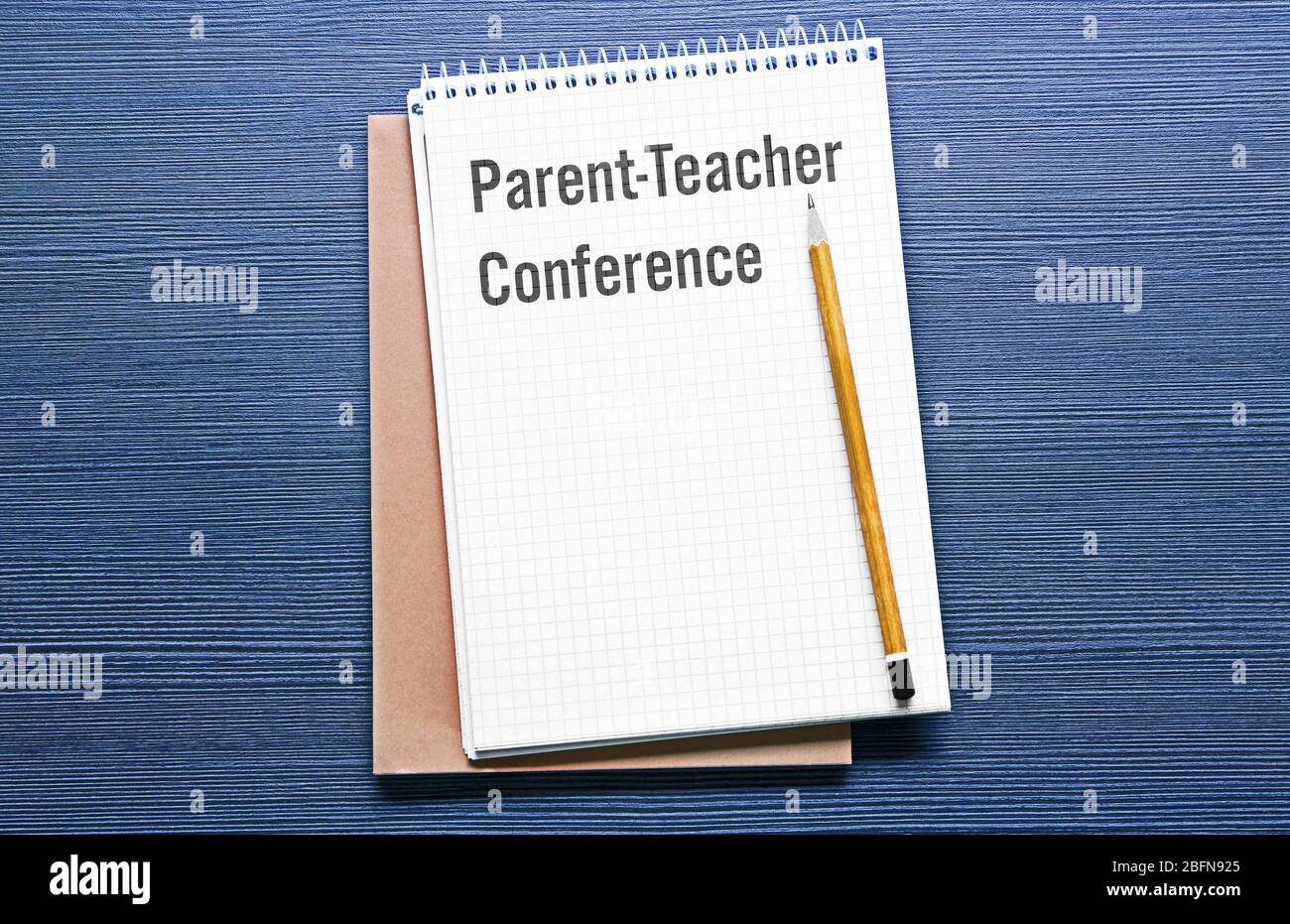 Text PARENT-TEACHER CONFERENCE written in notebook. Blue wooden background. School concept. Stock Photo