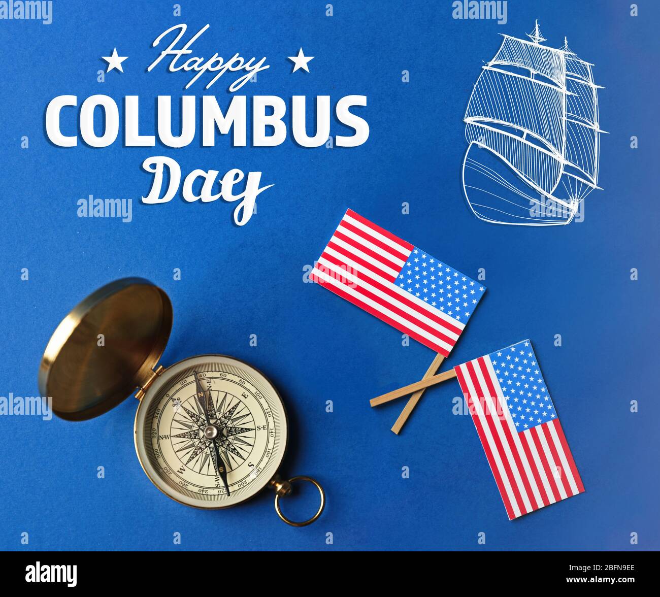 Text HAPPY COLUMBUS DAY with compass and USA flags on blue background. National holiday concept. Stock Photo