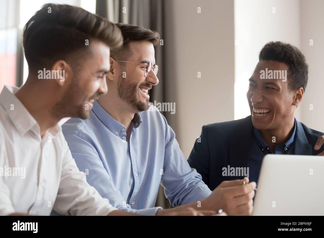 Diverse colleagues having fun telling anecdotes joking at workplace