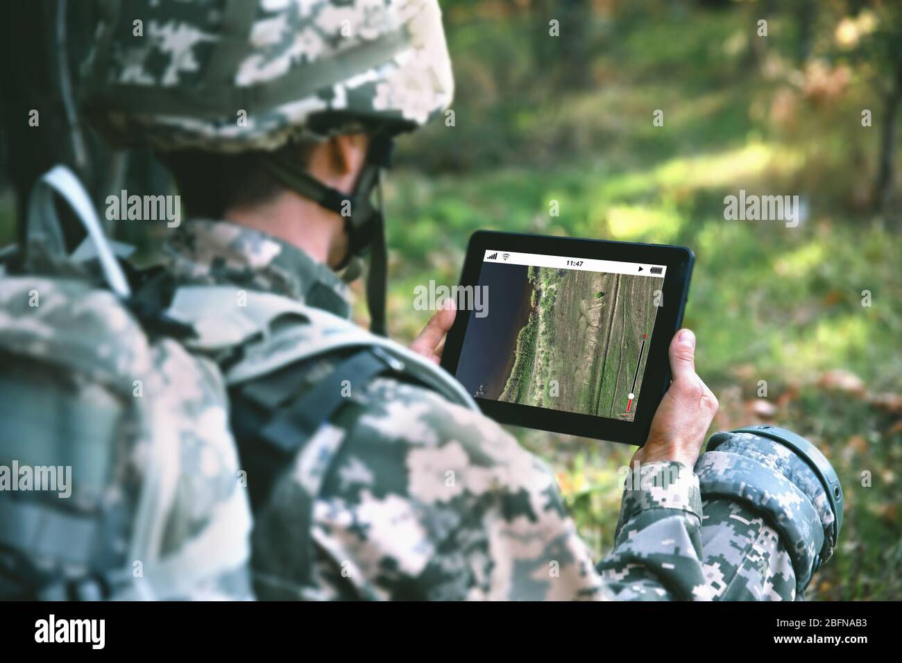 Soldier using map on tablet for orientation at forest Stock Photo