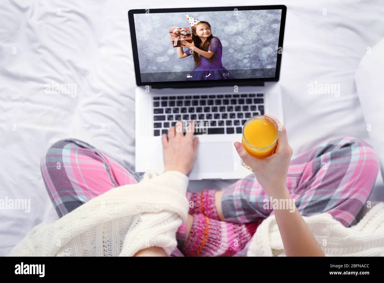 Woman talking to daughter via online video chat during birthday party Stock Photo