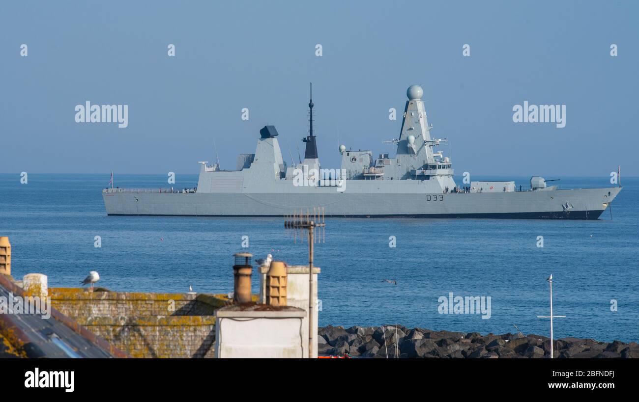 Lyme Regis, Dorset, UK. 19th April 2020. UK Weather: Royal Navy Type 45 Destroyer HMS Dauntless anchored near the Cobb at Lyme Regis on a warm and sunny afternoon during the coronavirus lockdown. An announcement was heard reminding the ship's company to stay 2 meters apart when on deck.  Credit: Celia McMahon/Alamy Live News. Stock Photo