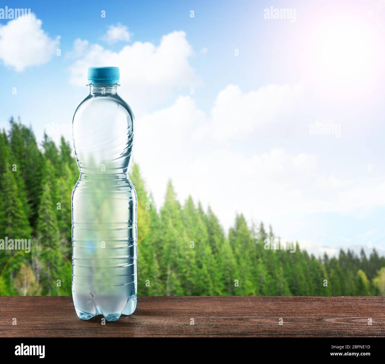 Bottle of clear water on wooden table against nature background Stock Photo
