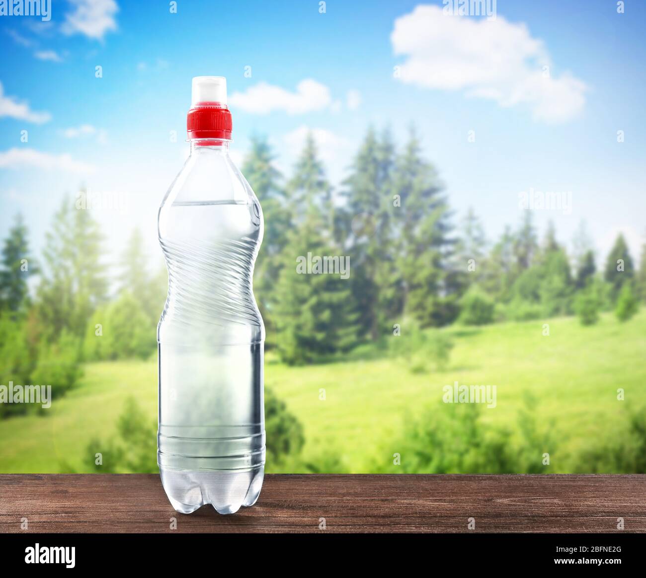 Bottle of clear water on wooden table against nature background Stock Photo