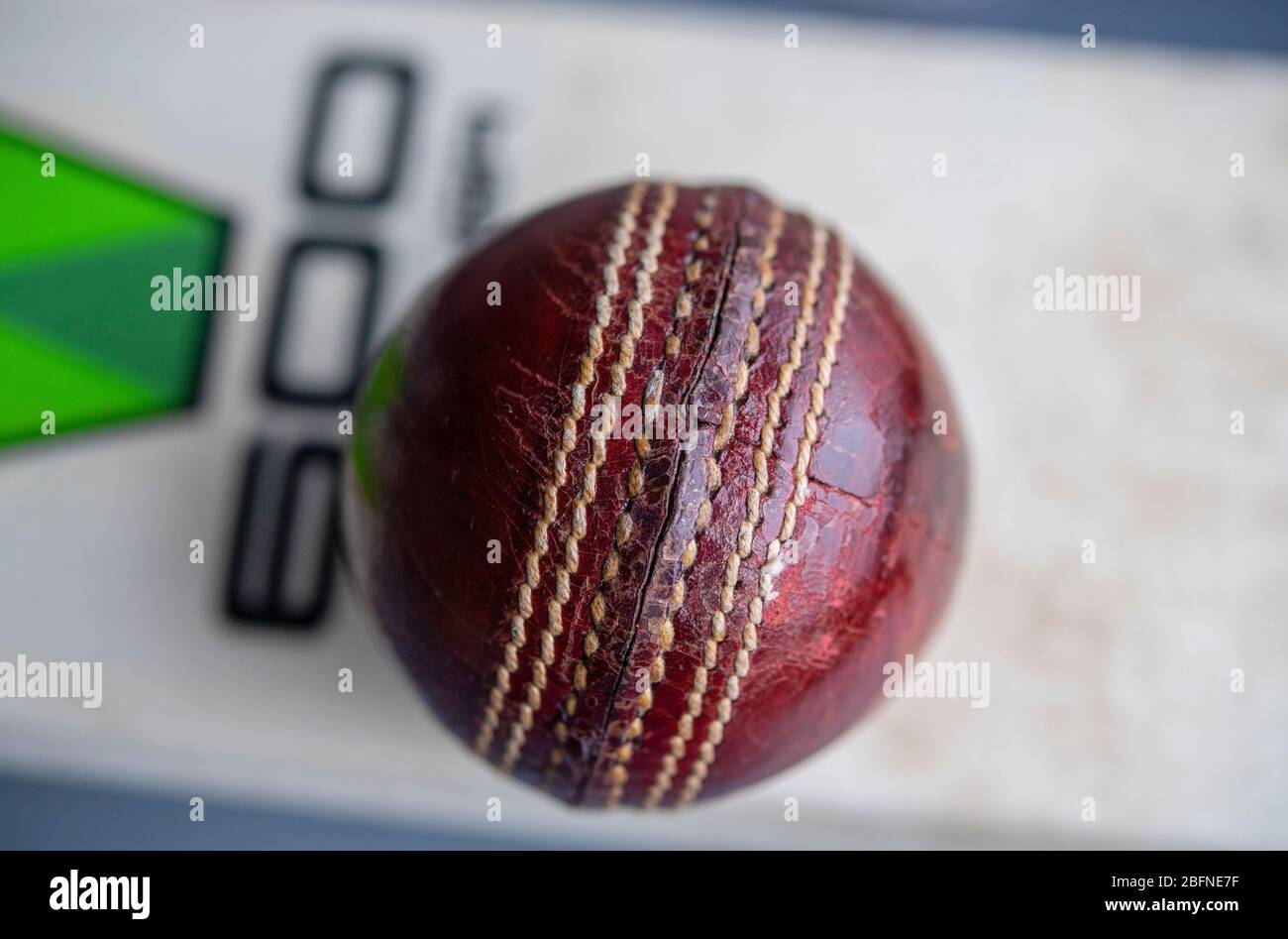 Cricket ball resting on a cricket bat Stock Photo