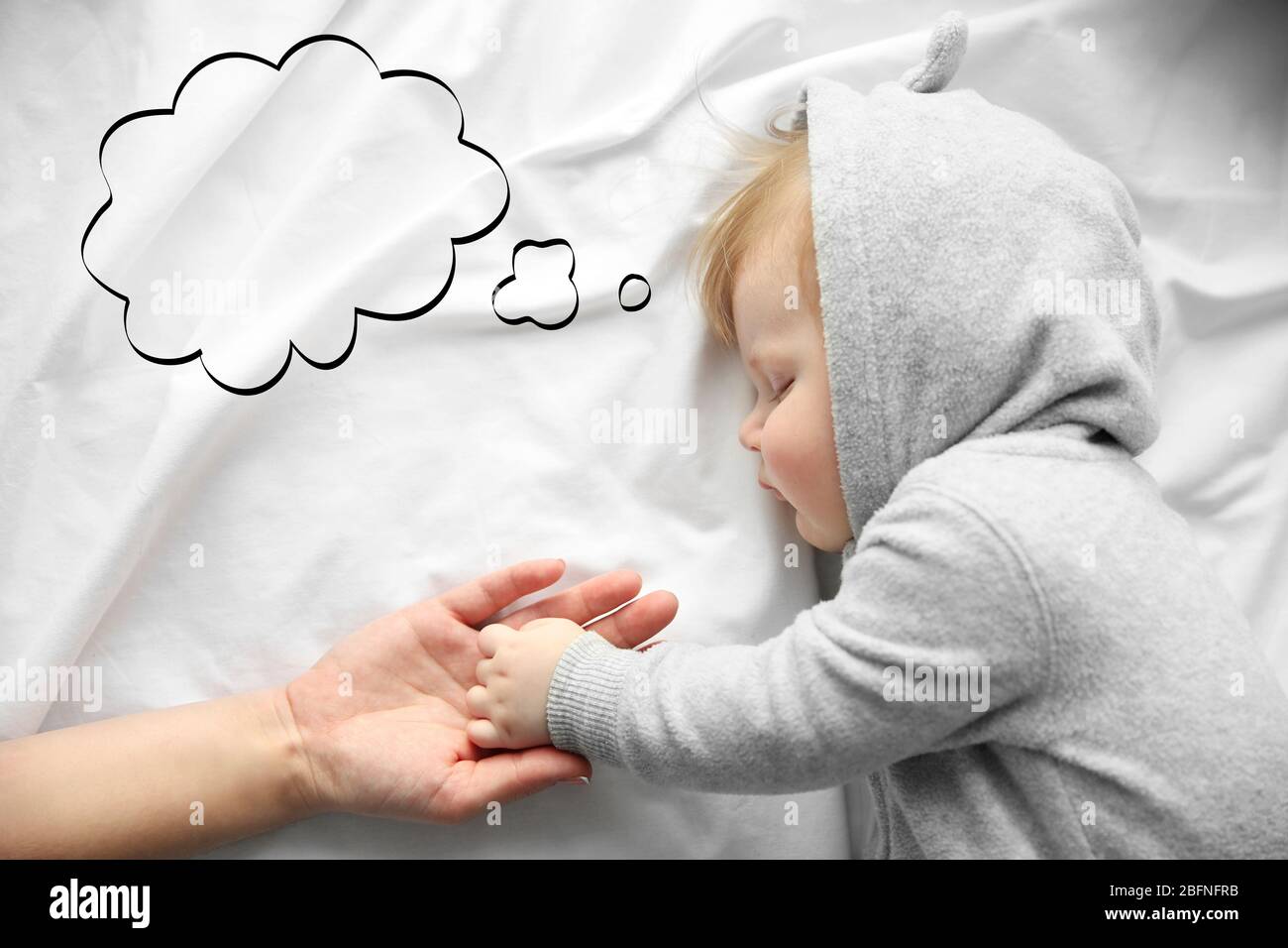 Mother holding hand of sleeping baby on bed Stock Photo Alamy