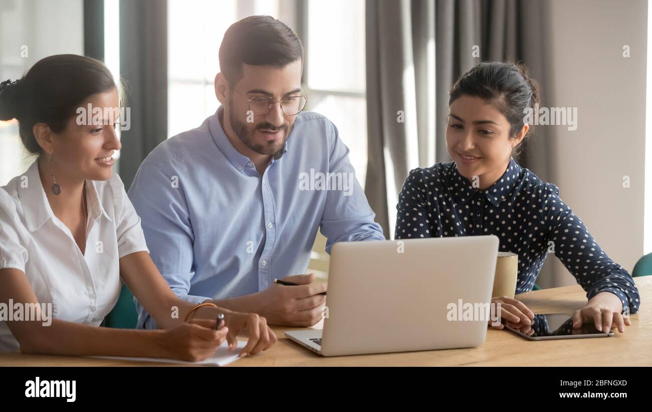 Three diverse teammates looking at computer screen discussing project Stock Photo