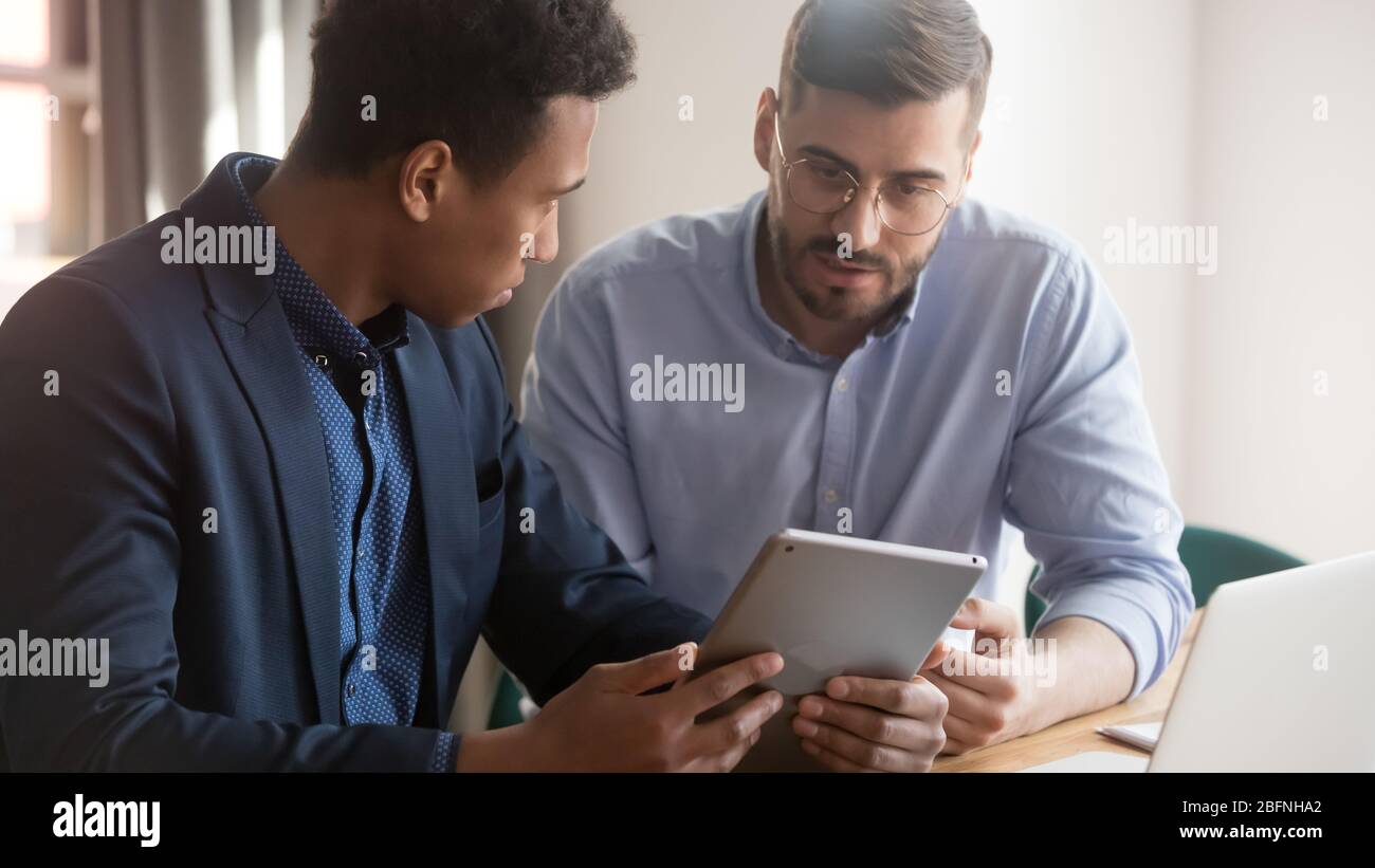 Multi-ethnic business partners discuss project using tablet device Stock Photo