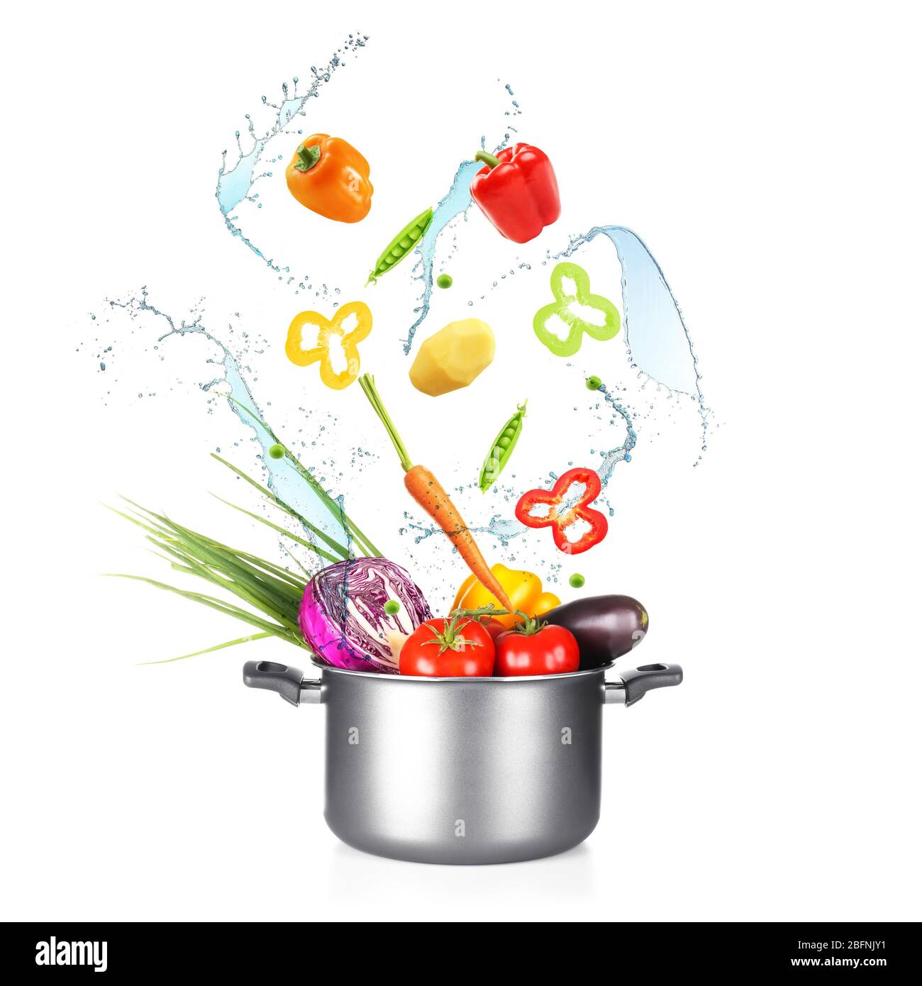 Different vegetables, water splashes and saucepan on white background Stock Photo