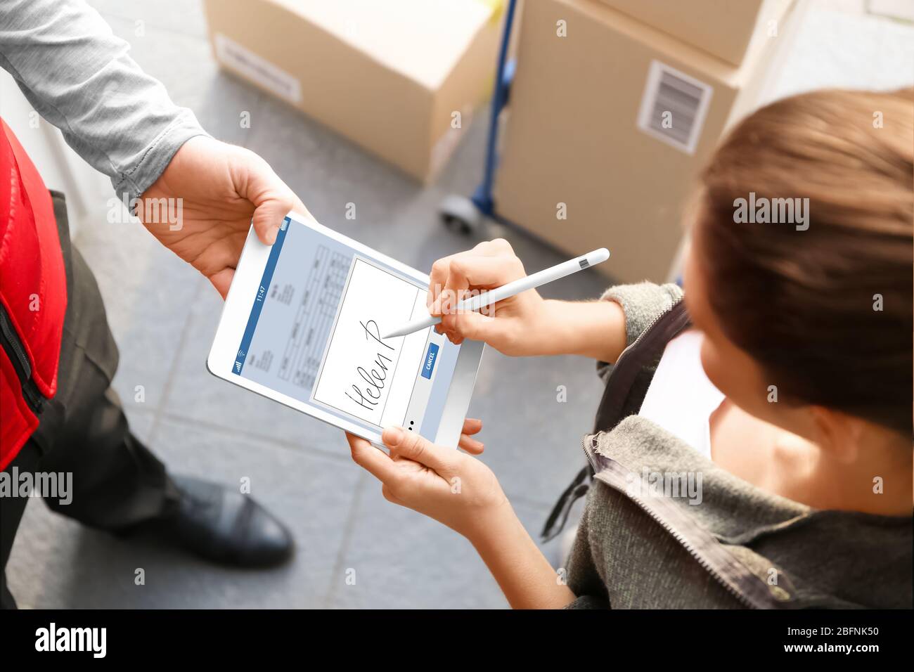 Woman appending signature after receiving parcel from courier outdoors Stock Photo