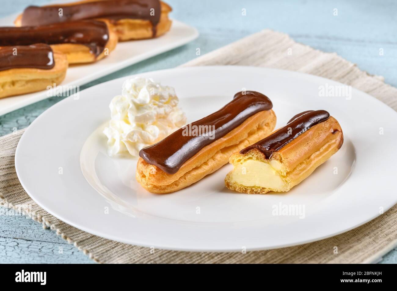 Eclairs with chocolate topping on serving plate Stock Photo