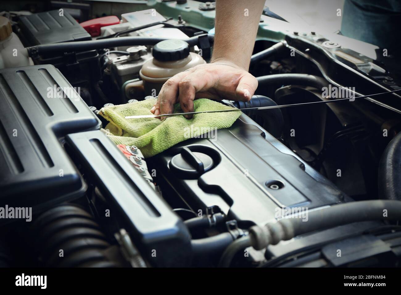 Auto mechanic checking engine oil level in body shop Stock Photo