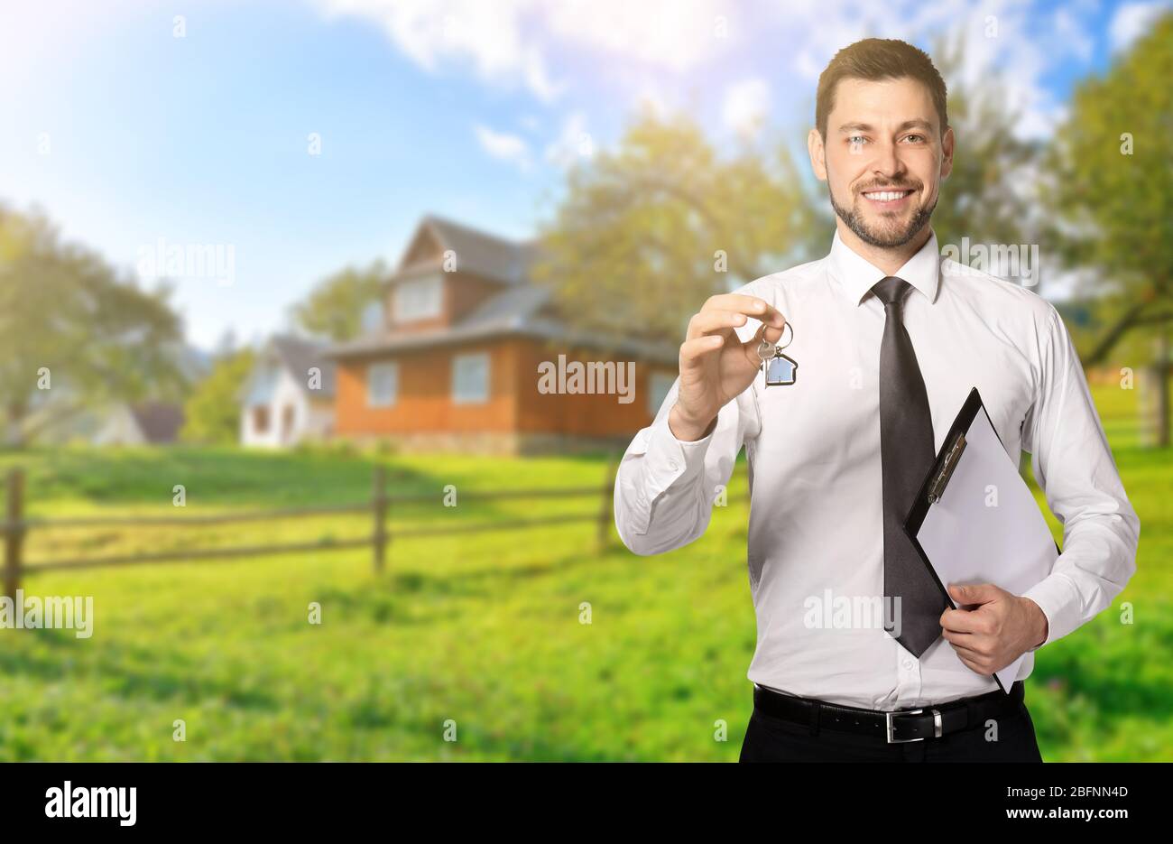 Real estate agent holding key in front of country house outdoors Stock ...