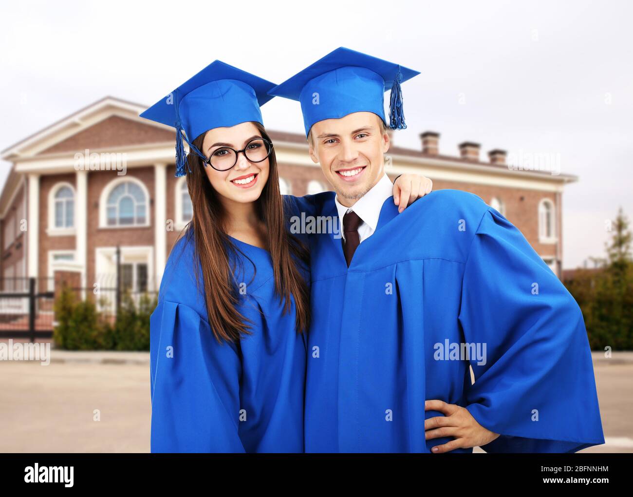 Students in graduation gowns and caps on campus territory Stock Photo