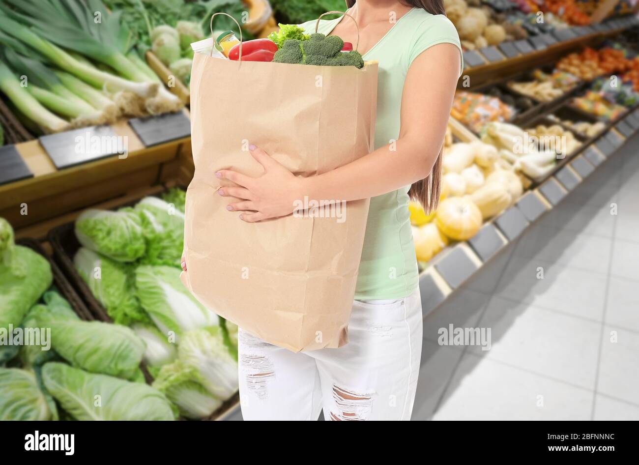 Young woman holding paper bag with groceries after shopping in supermarket  Stock Photo - Alamy