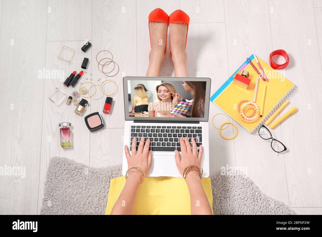 Woman sitting on floor with laptop and watching online training for professional makeup artist Stock Photo
