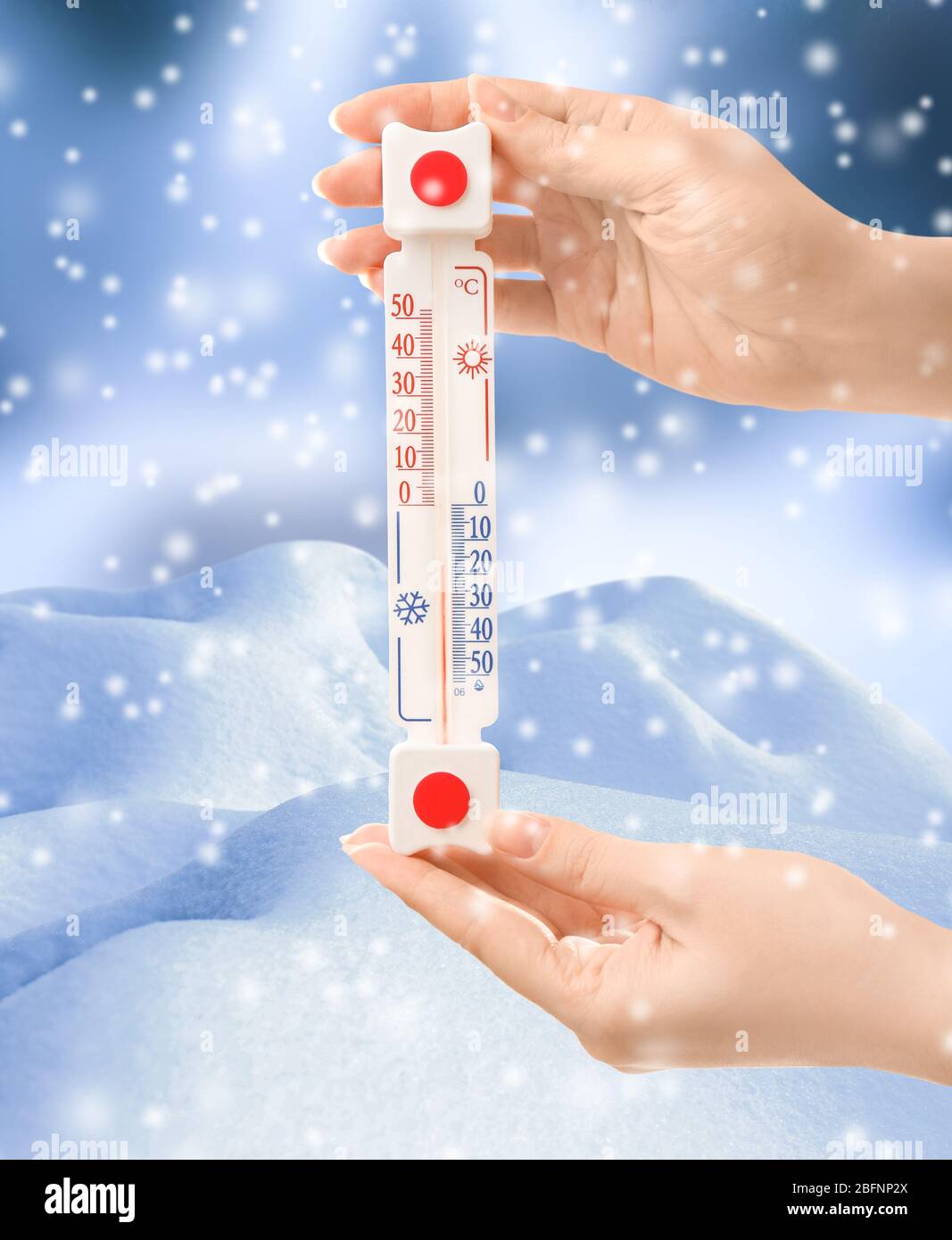 Woman with thermometer registering temperature below zero outdoor Stock Photo