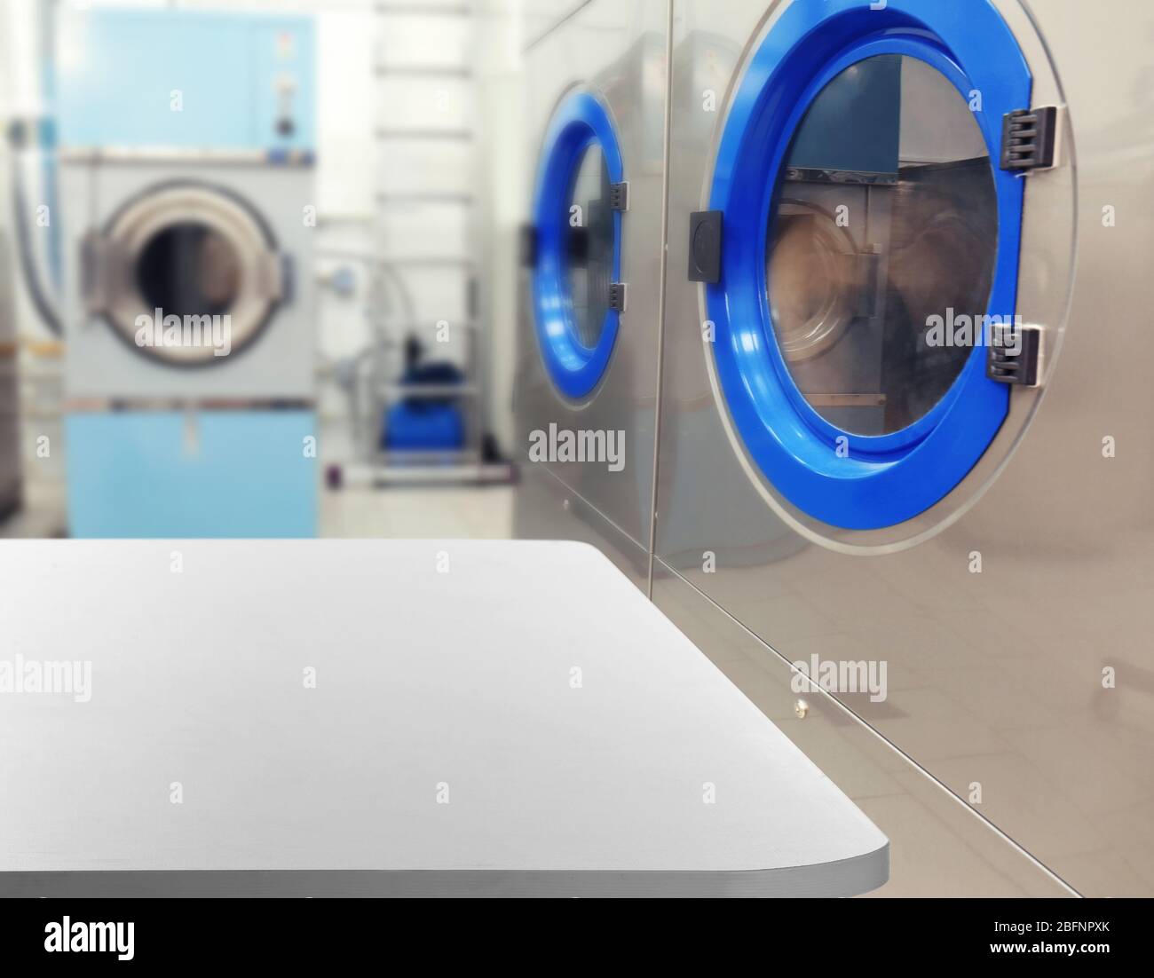 Table and washing machines at self-service laundry Stock Photo