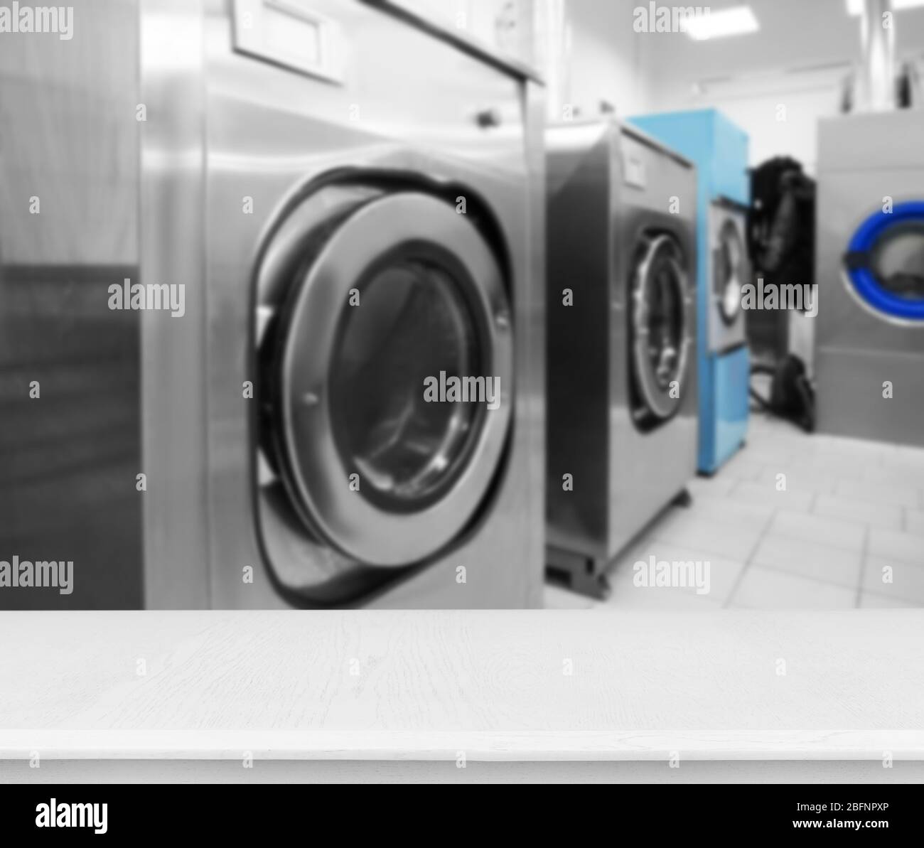 Table and washing machines at self-service laundry Stock Photo