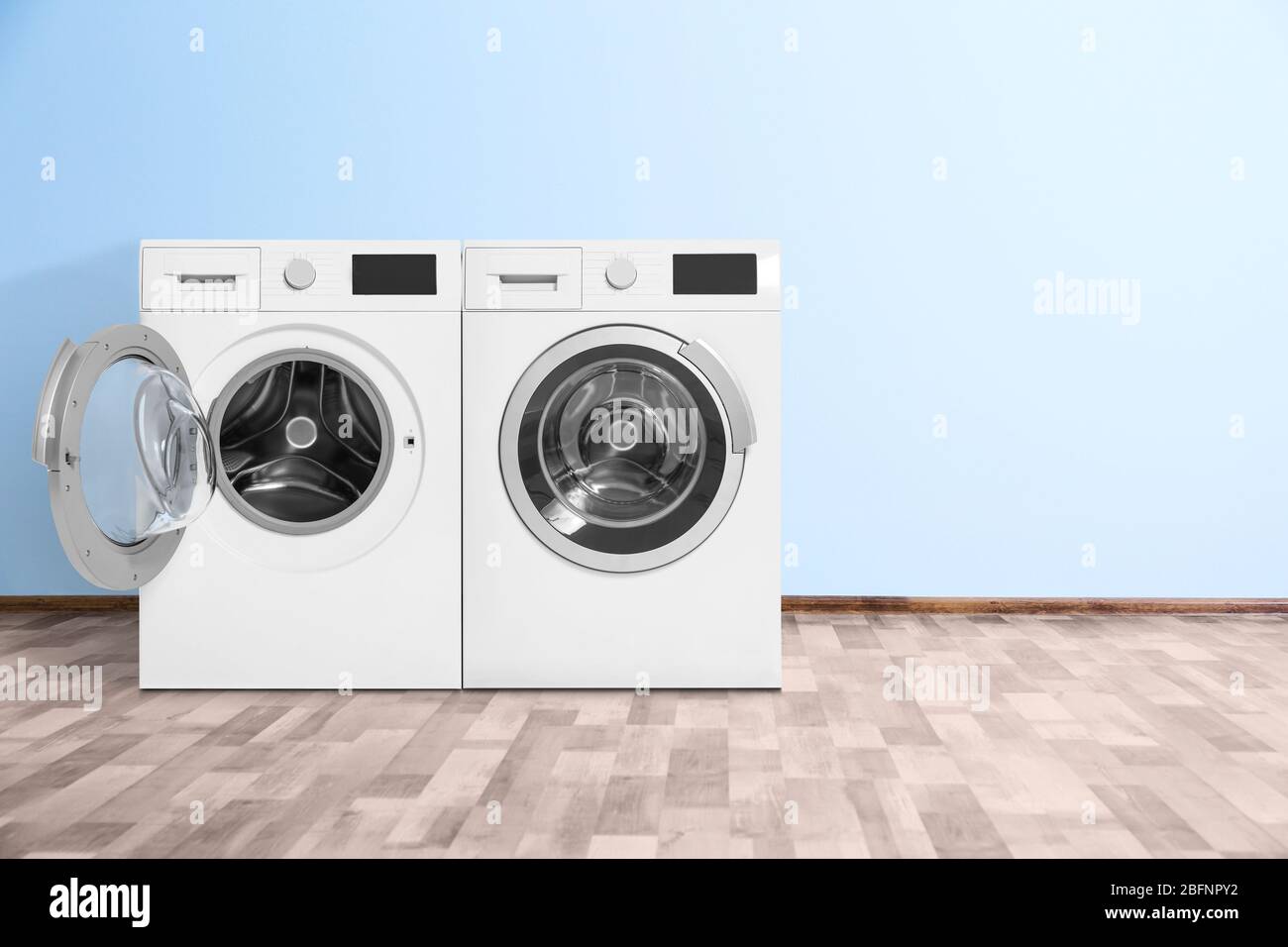 Modern washing machines near color wall indoors. Laundry day Stock Photo