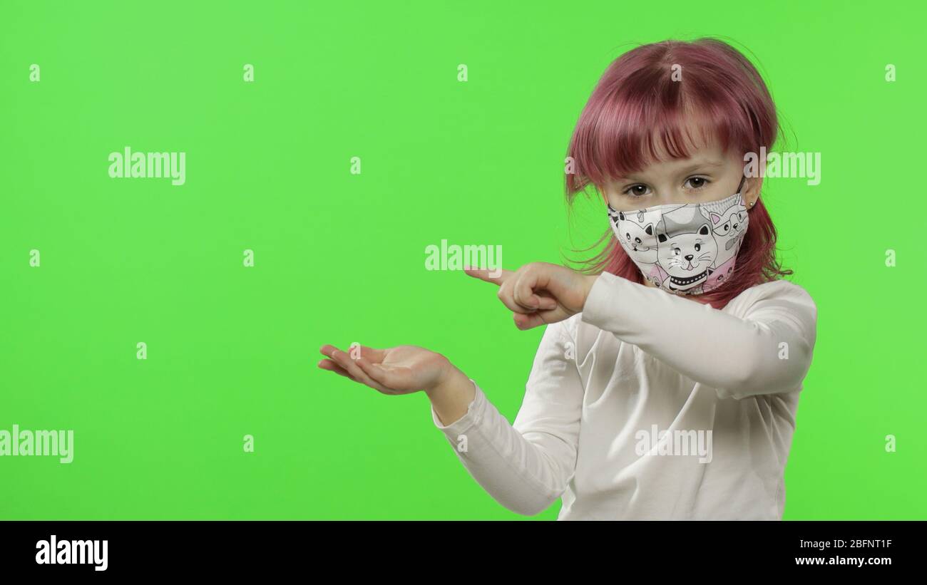 Portrait of little girl showing something. Medical face protective mask ...