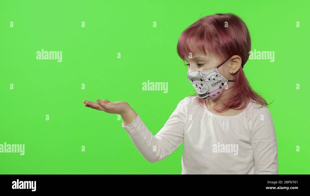 Portrait of little girl showing something. Medical face protective mask ...