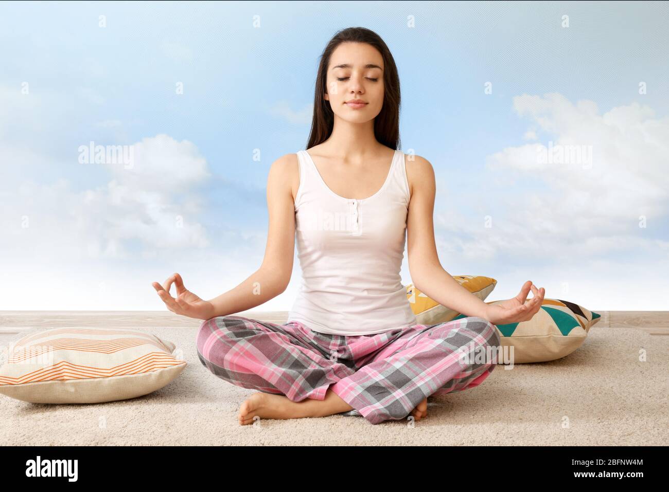 Young woman meditating in lotus pose on sky background. Concept of ...
