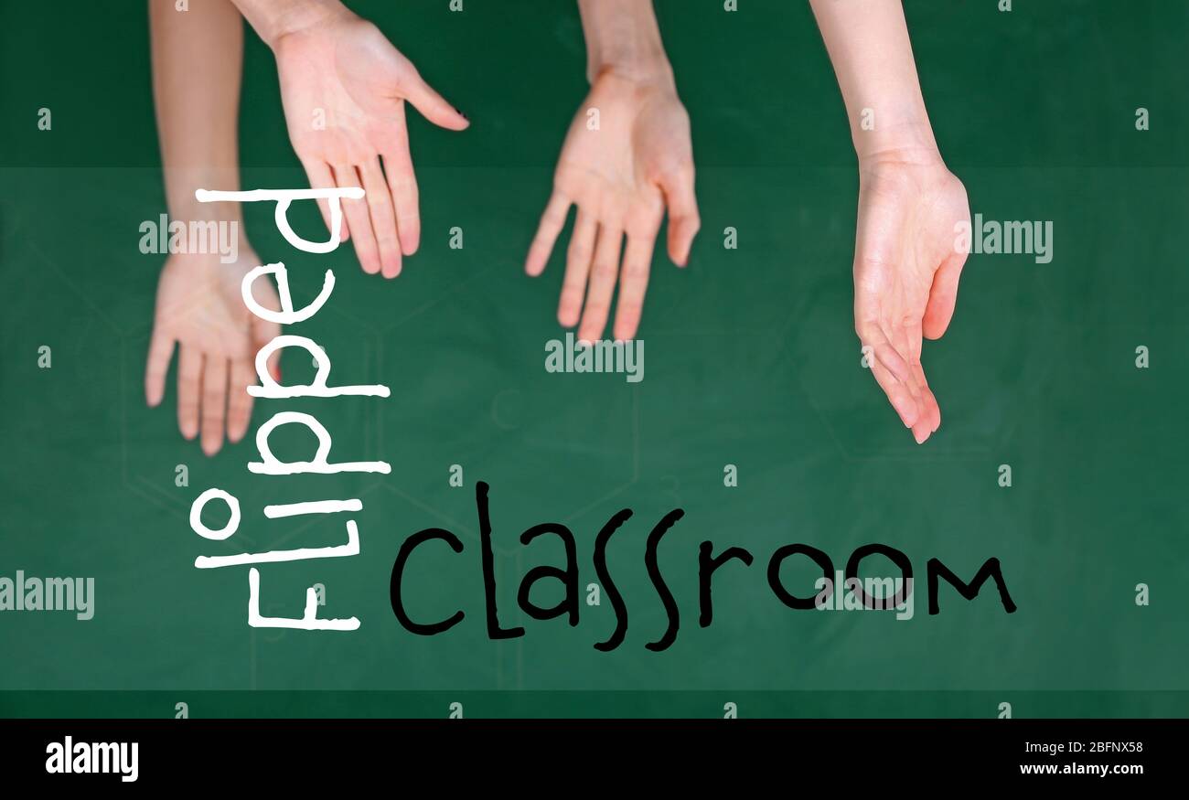 Flipped classroom concept. Inversed children's hands on blackboard background Stock Photo