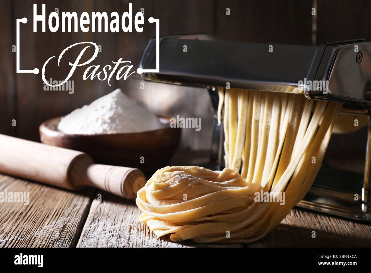 Raw homemade pasta and machine on wooden table Stock Photo