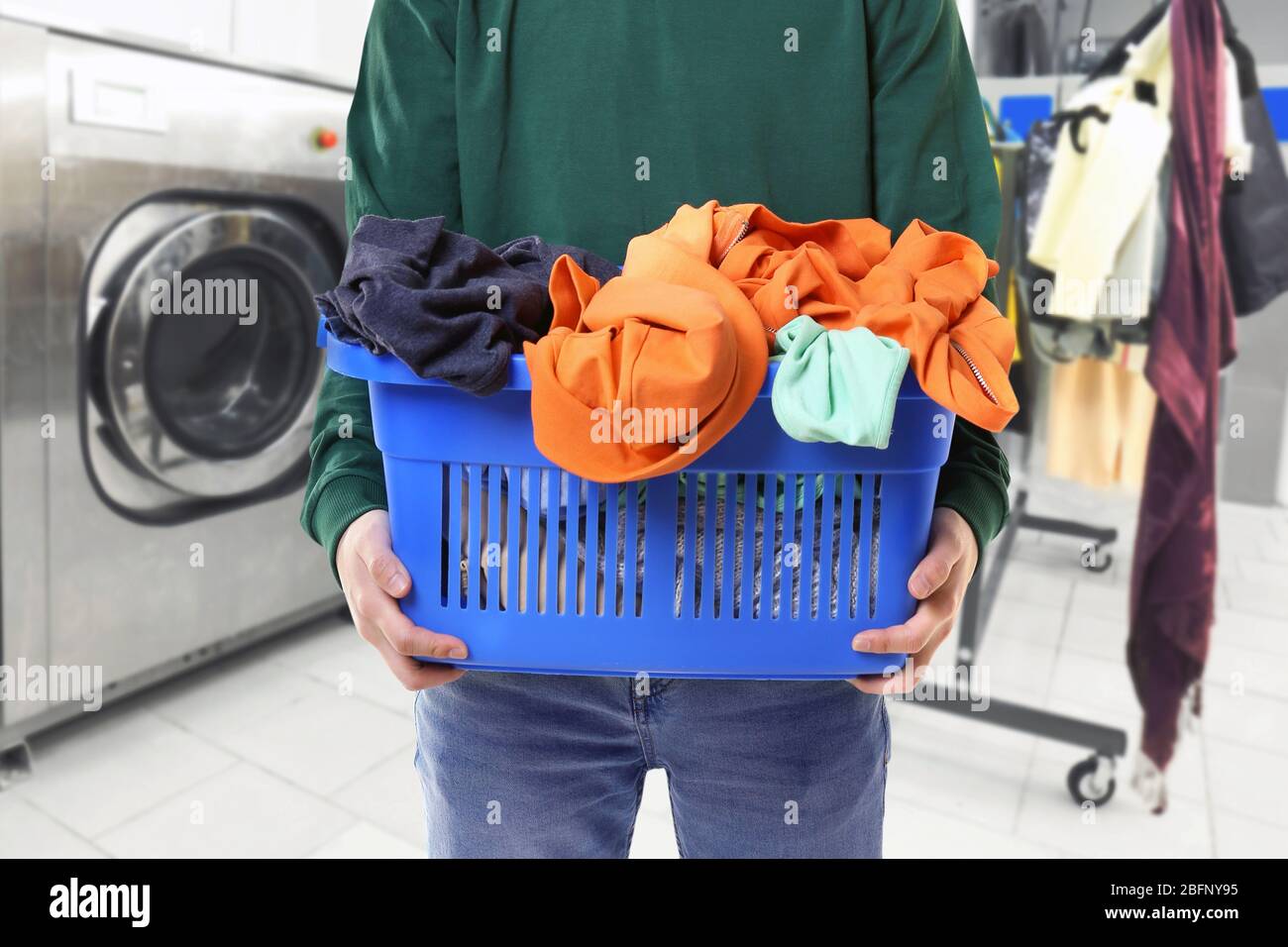 Dry cleaning concept. Man holding basket with clothes at laundry Stock Photo