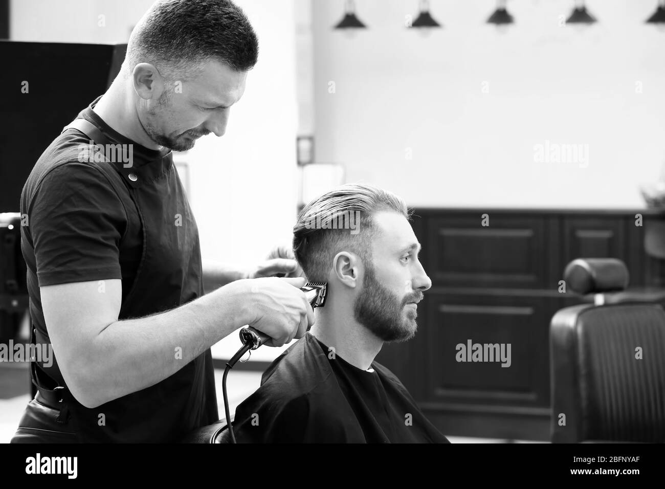 Hairdresser working with customer at barbershop Stock Photo