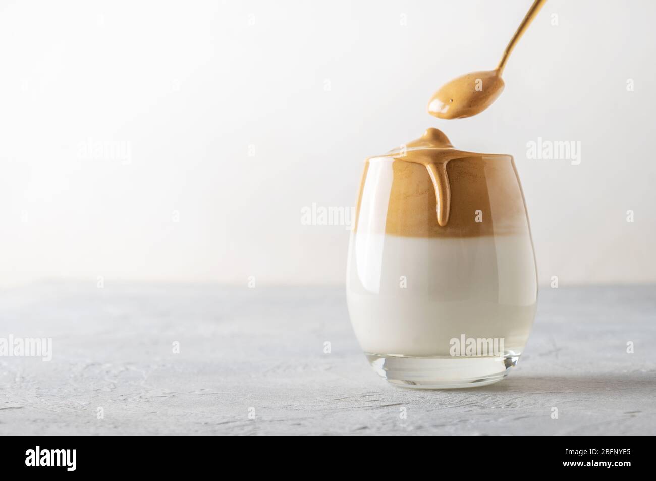 Korean drink Dalgona coffee in glass with milk with and instant coffee on white background. Copy space. Stock Photo