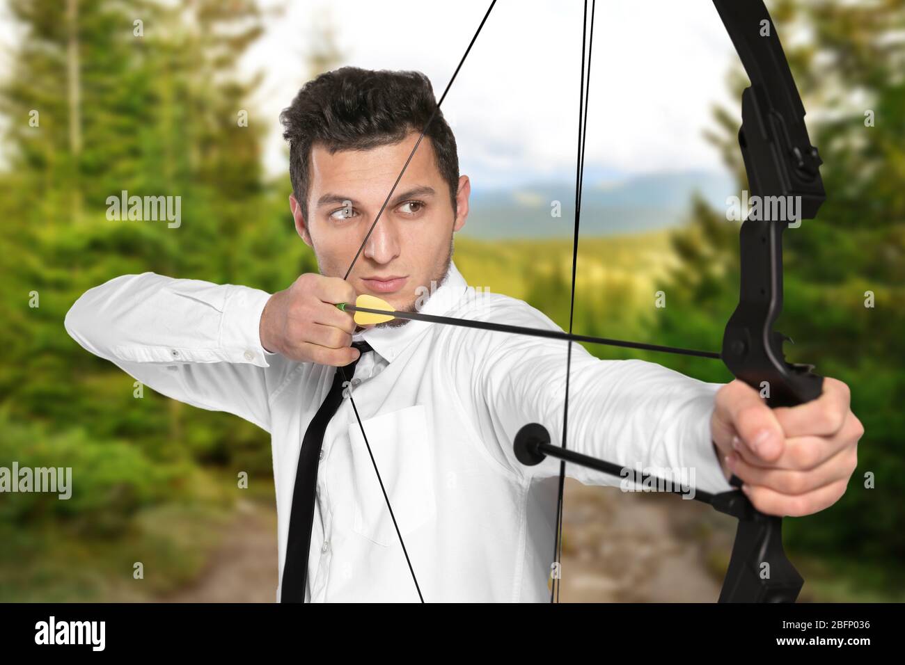 Young businessman practicing archery and landscape on background Stock Photo