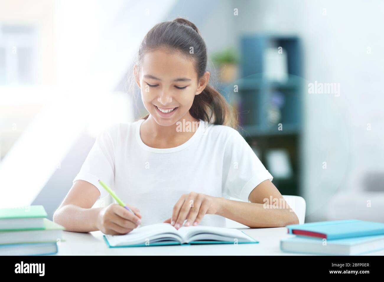 Girl doing homework at table in room Stock Photo