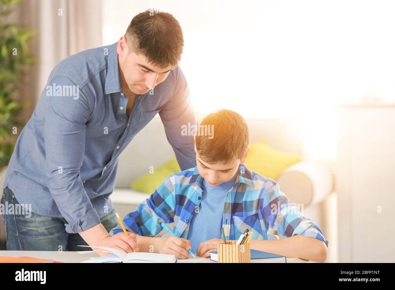Father helping son with homework in room Stock Photo - Alamy