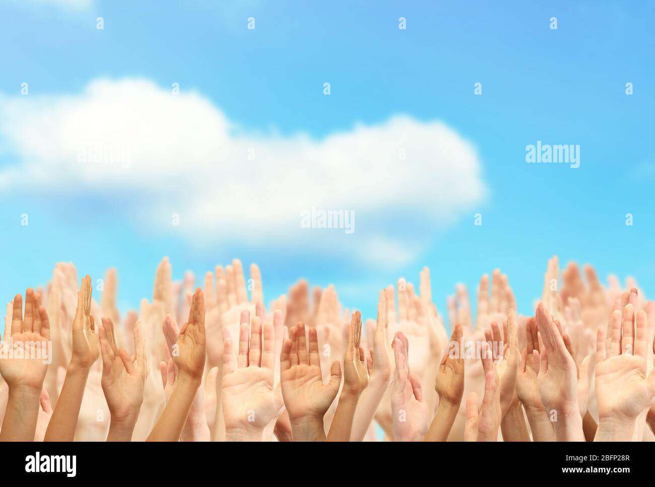 Crowd raising hands on blue sky background Stock Photo - Alamy