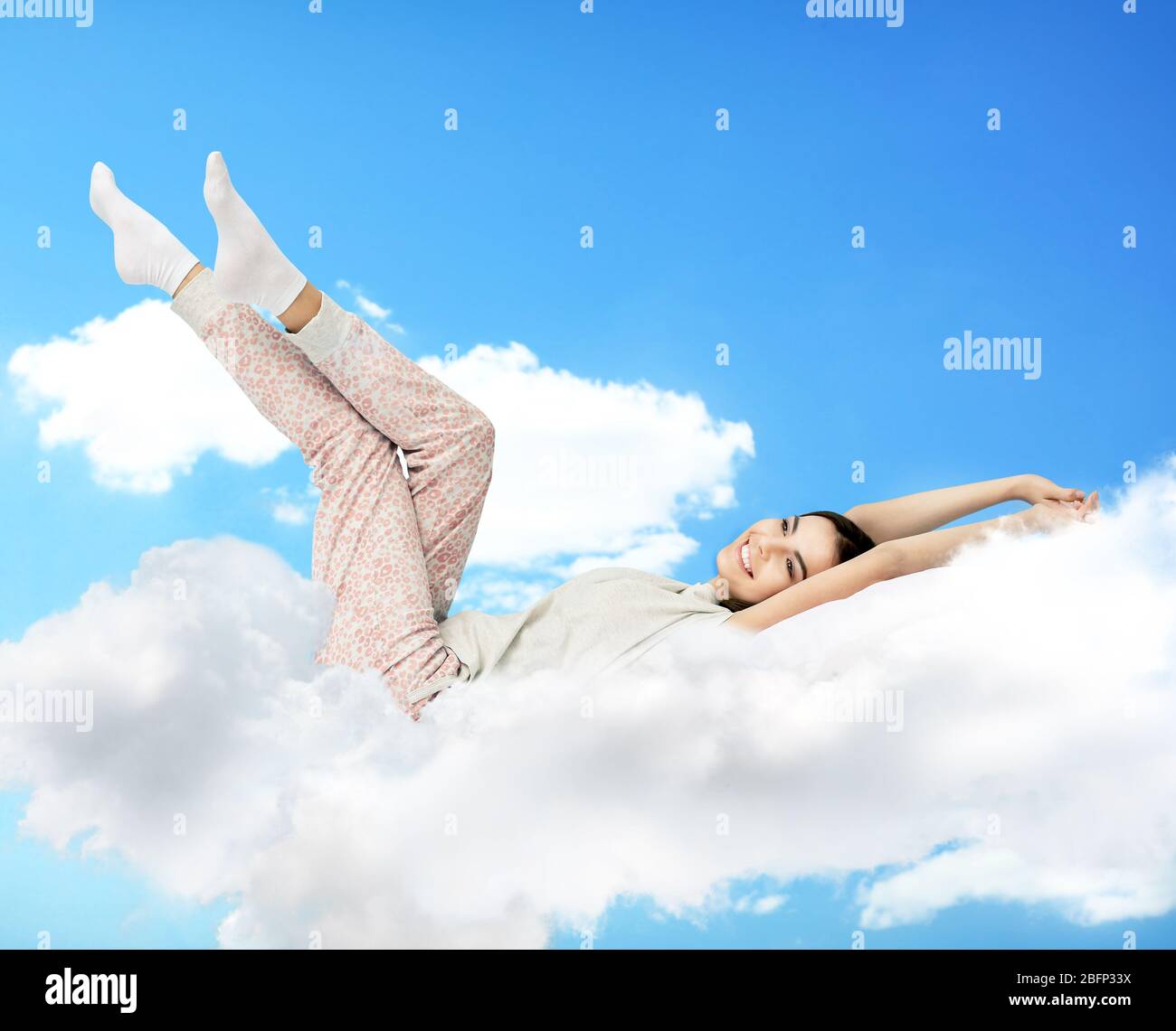 Beautiful girl lying on blue cloudy sky Stock Photo - Alamy