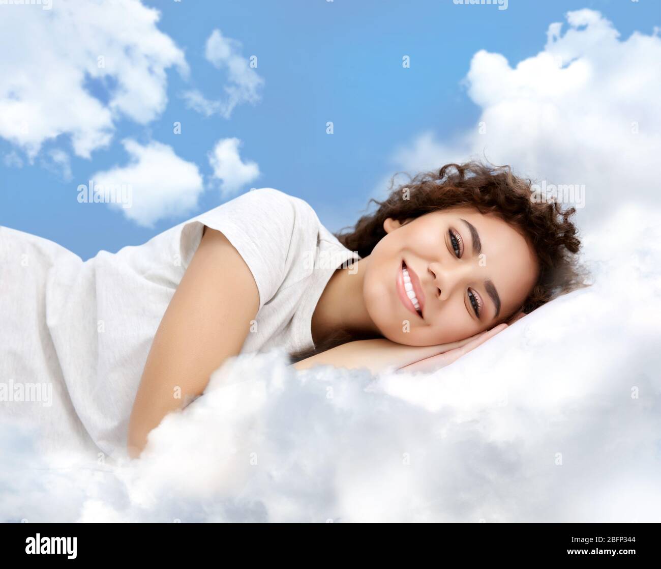 Beautiful girl lying on blue cloudy sky Stock Photo - Alamy