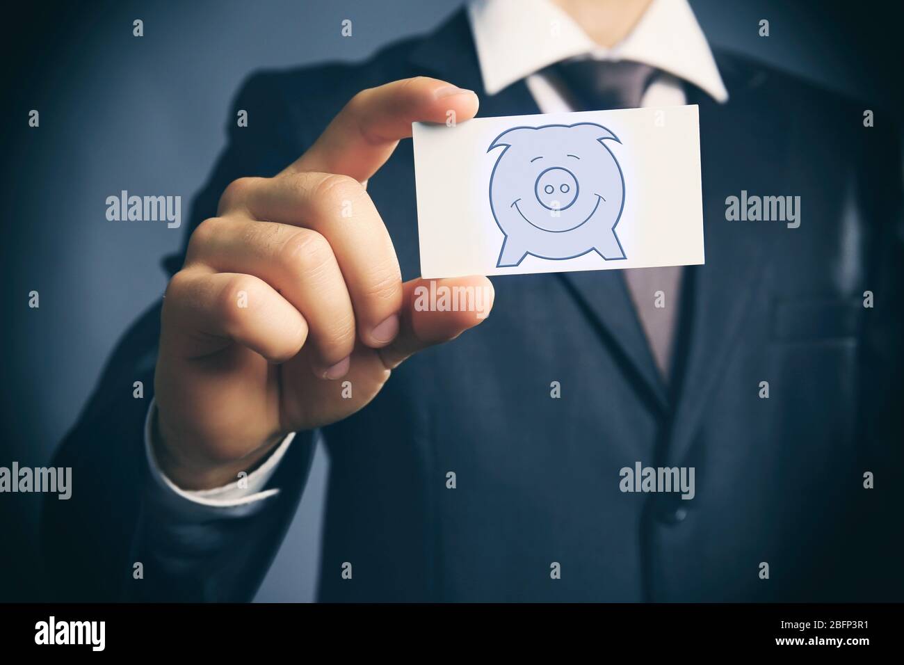 Elegant man in suit holding business card with picture of piggy bank ...