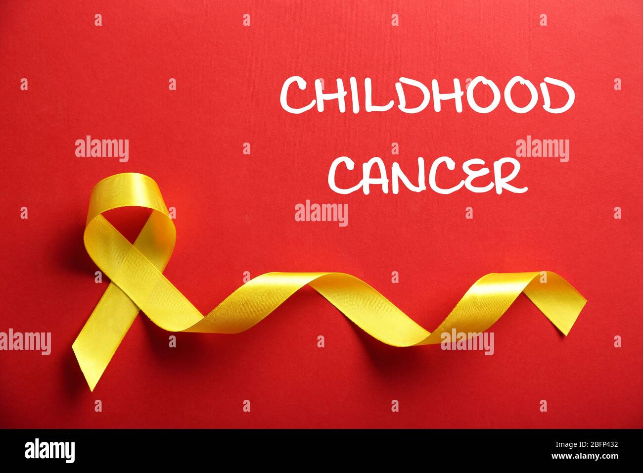 Yellow ribbon and text Childhood Cancer on red background Stock Photo